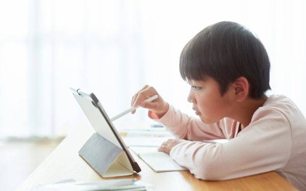 真剣な表情でタブレットをタッチペンでクリックする男の子