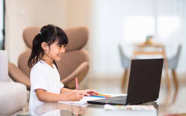 ノートパソコンを見ながらレプトンのテキストに文字を書く女の子