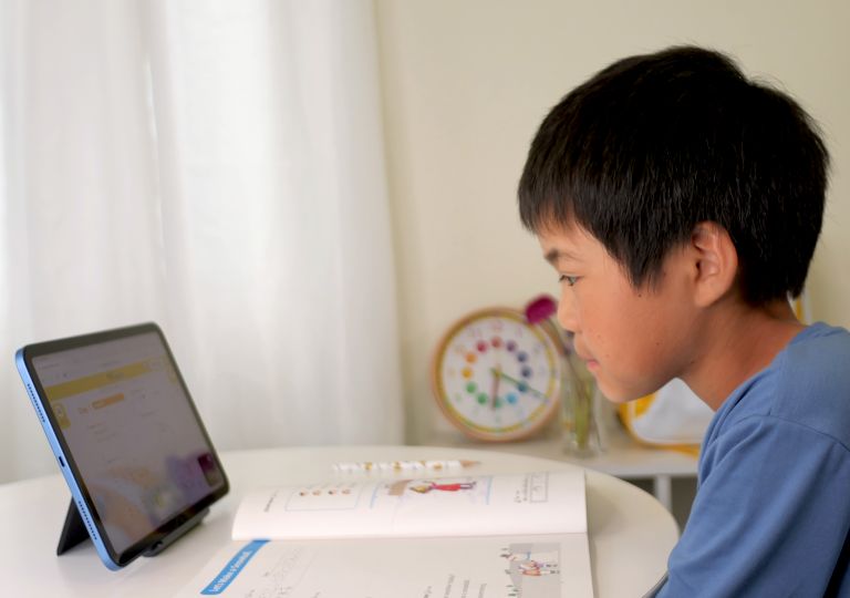 タブレットに集中して何かを聞き取ろうとする子どもの写真